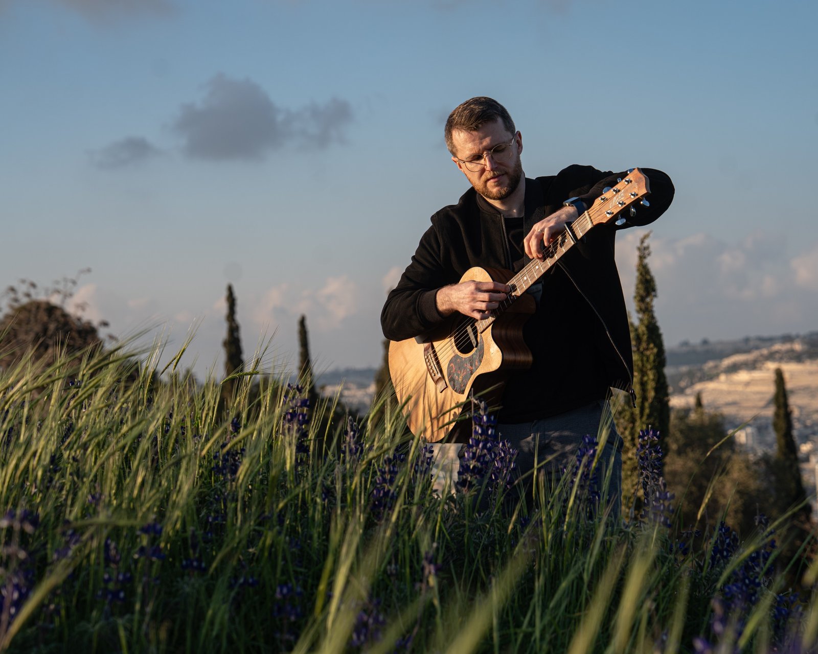 David Niskin playing acoustic guitar outdoors.